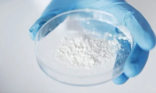 Handschoen houdt petrischaal met ACell-poeder, een regeneratief biomateriaal dat gebruikt wordt bij haartransplantaties.