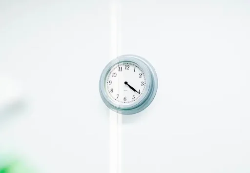 Minimalistische wandklok aan witte muur in de wachtruimte van een haartransplantatiekliniek.