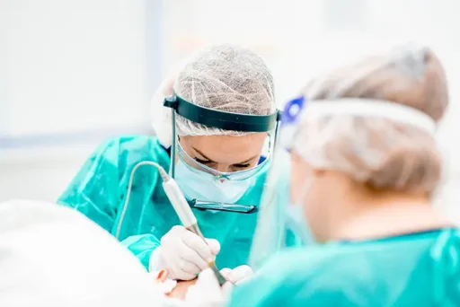 Team van chirurgen in groene operatiekleding voert de FUE‑haartransplantatiemethode uit.