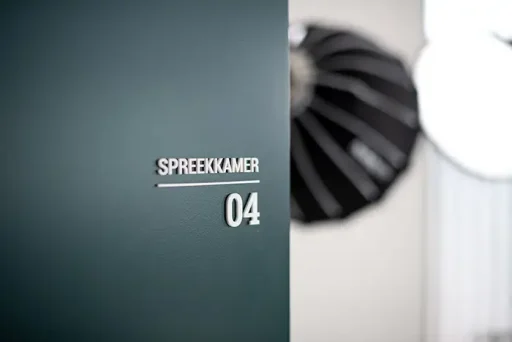 Bord met opschrift 'spreekkamer 04' op de deur van de kliniek voor haartransplantatieconsult.