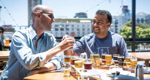 Twee mensen proost met alcoholische drankjes – invloed van alcohol op haartransplantatie.