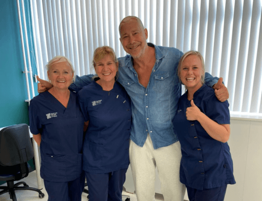 Hans Kesting na zijn haartransplantatie, samen met drie specialisten van de Zantman Kliniek in een ontspannen en professionele setting.