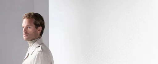 Een man met een volle haardos kijkt zelfverzekerd weg, symbool voor het natuurlijke resultaat van een haartransplantatie.