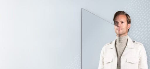 Een man kijkt in de spiegel met een vernieuwde haarlijn – een symbool voor de transformatie na een haartransplantatie.