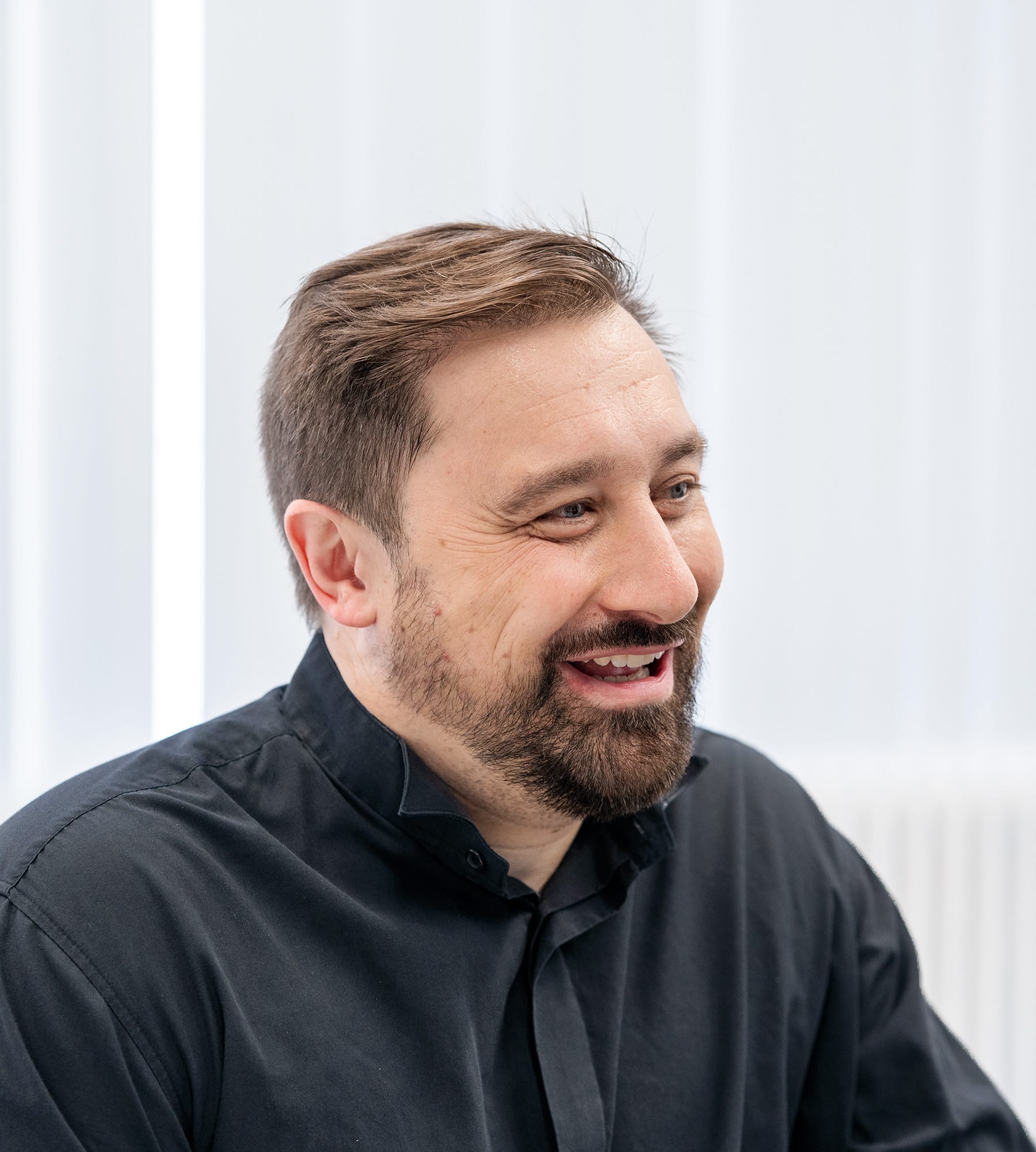 Lachende man met kort haar in zwarte blouse, gebruikt als omslagfoto