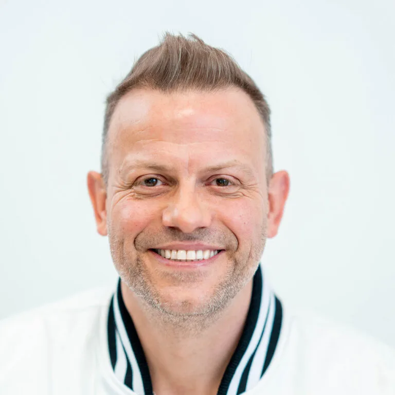 Close-up van Joost Seilberger na zijn haartransplantatie met een volle nieuwe haarlijn en glimlach.